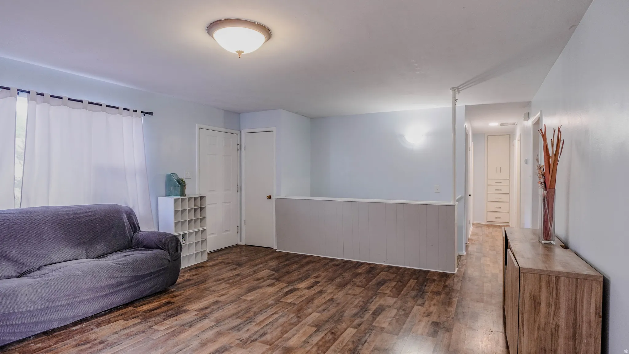 Wood-finish flooring throughout, white paneled wall accent, and a built-in hallway cabinet with drawers and upper storage