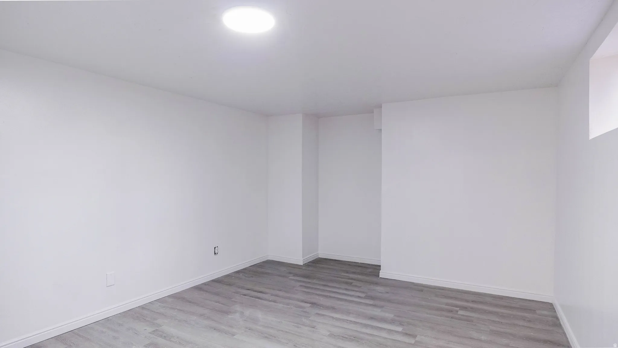 Recessed ceiling lighting, wood-finish flooring, white painted walls, and a small window
