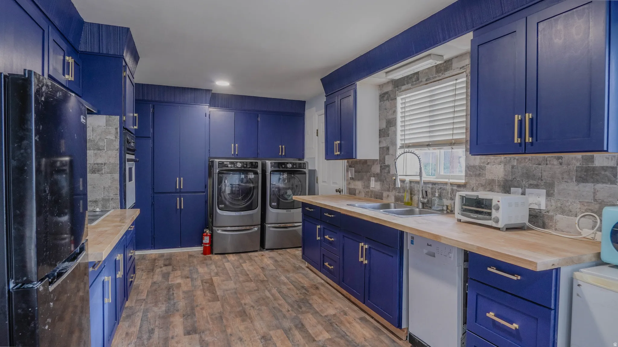 Full-height cabinetry, wood-finish flooring, two-tone backsplash, wood countertops, and stainless-steel appliances