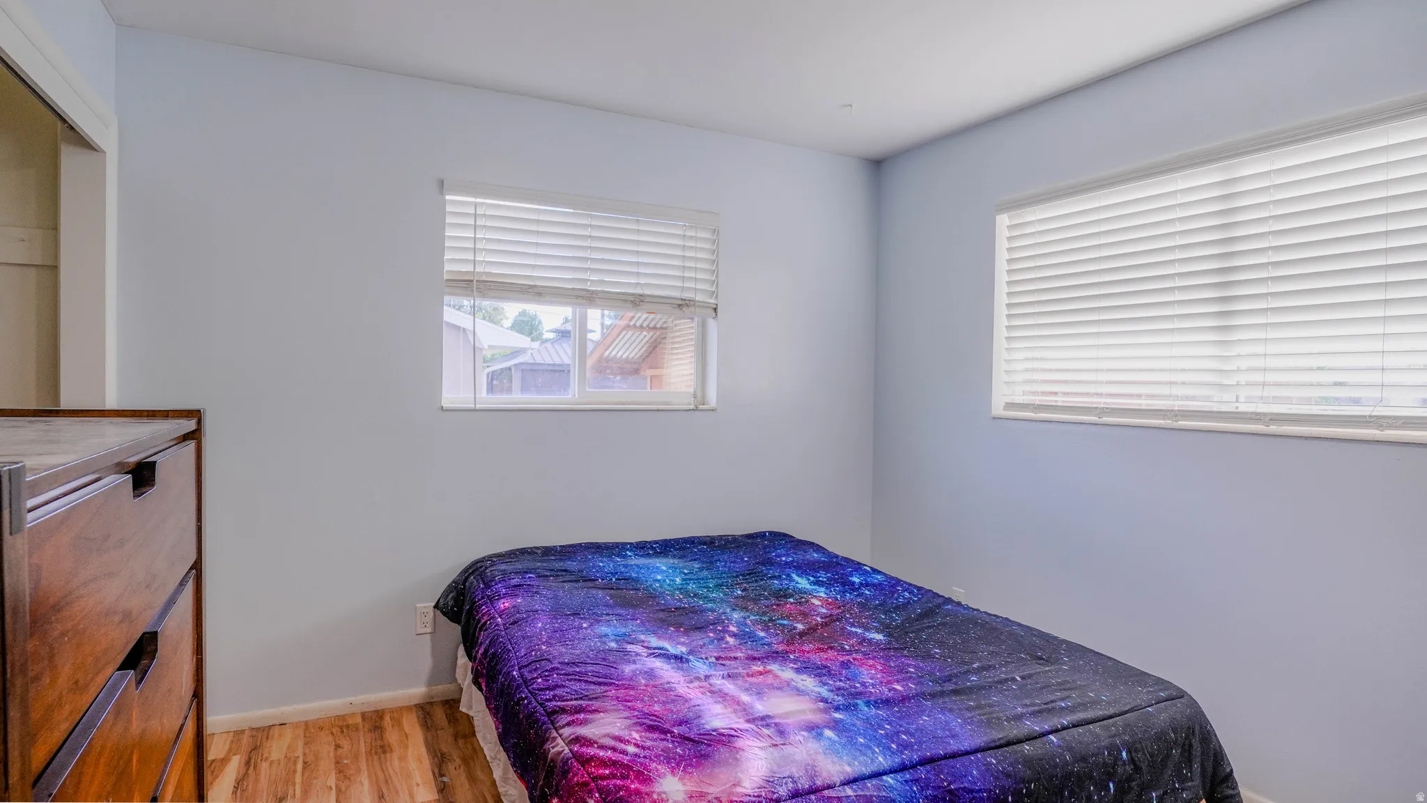 Light-toned walls, wood-finish flooring, and multiple windows with blinds