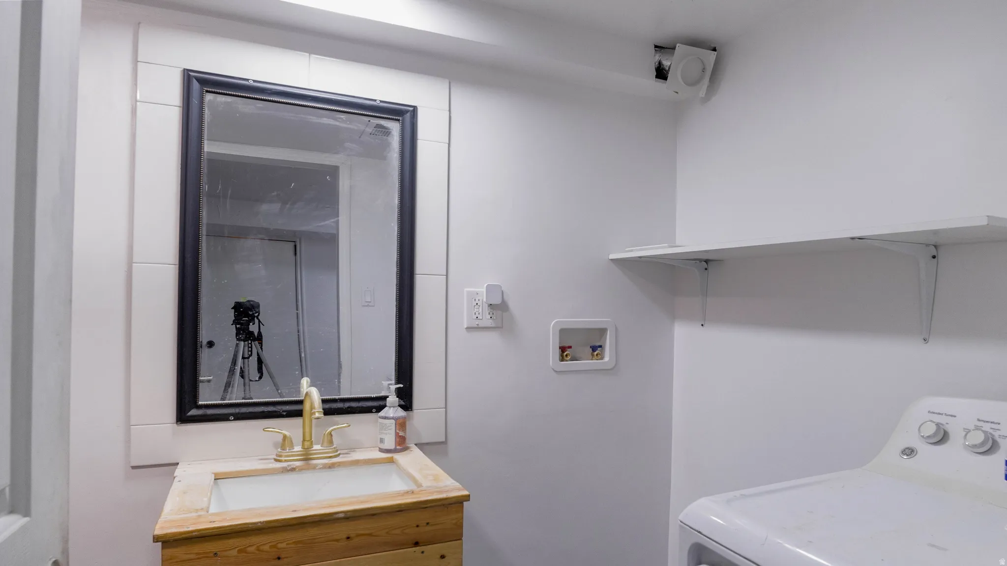 Wall-mounted shelving, wood-finish vanity with an integrated sink, and a framed mirror