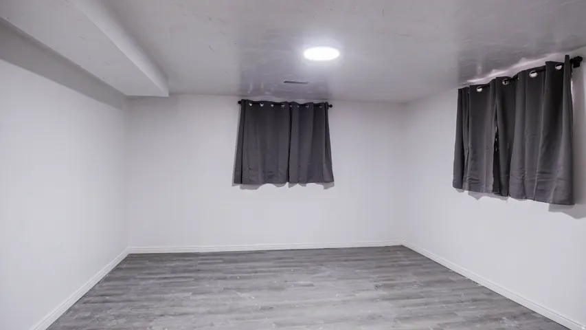 White walls with a single recessed ceiling light and wood-finish flooring