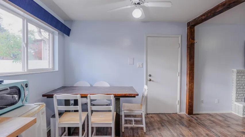 Wood-finish flooring, white ceiling fan with light, and a white door with silver-tone hardware