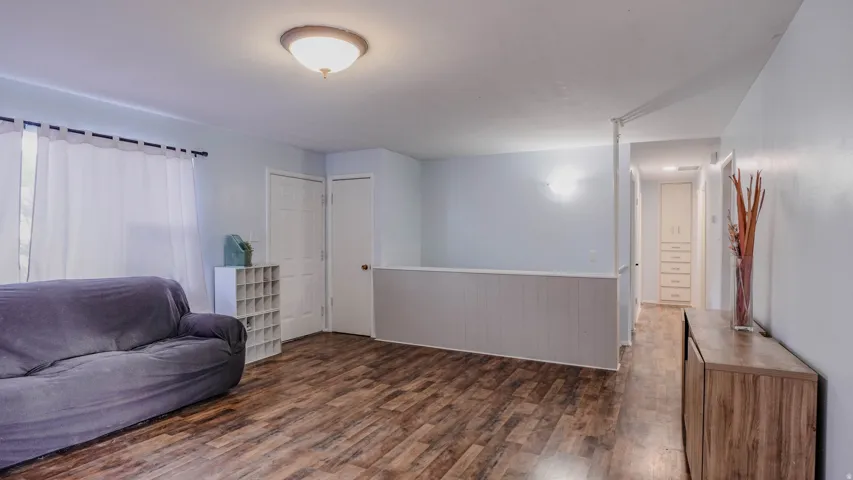 Wood-finish flooring throughout, white paneled wall accent, and a built-in hallway cabinet with drawers and upper storage