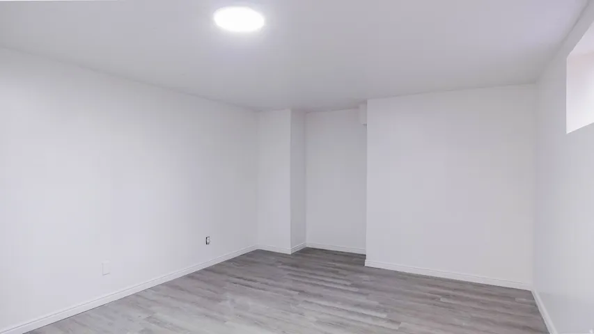 Recessed ceiling lighting, wood-finish flooring, white painted walls, and a small window