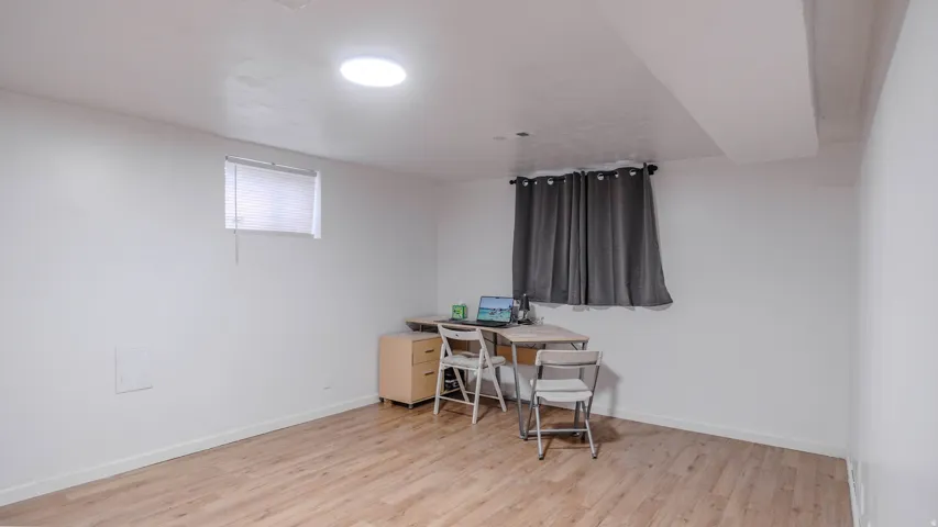 Recessed ceiling lighting, wood-finish flooring, and a window with blinds