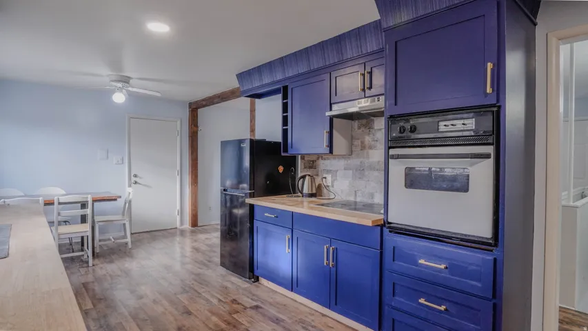 Kitchen featuring blue cabinetry, light wood-finish countertops, and a built-in oven