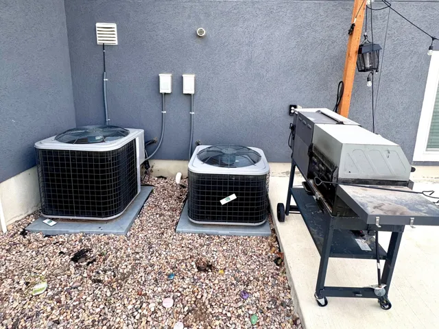 Dual exterior HVAC units on a gravel bed, concrete patio, and stucco exterior