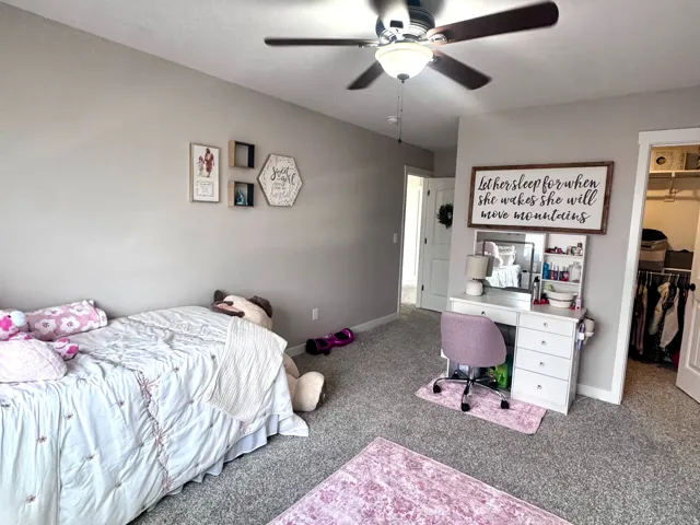 Ceiling fan with integrated lighting, neutral wall tones, carpeted flooring, and a built-in closet with shelving