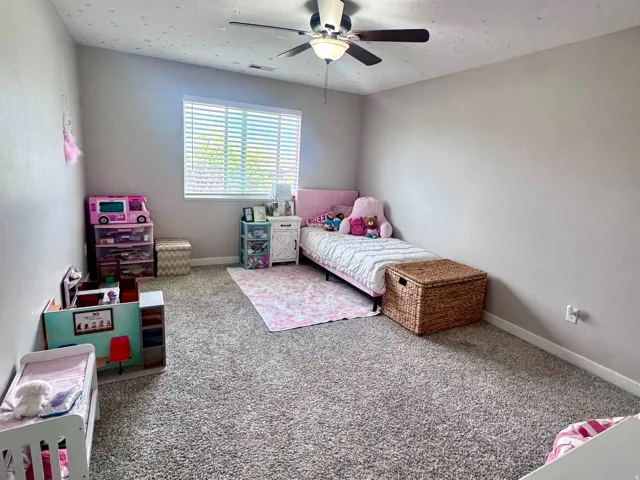 Spacious room featuring neutral carpeting, a ceiling fan with integrated lighting, and a window with blinds