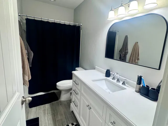 White vanity with integrated sink, chrome fixtures, and a four-light vanity bar