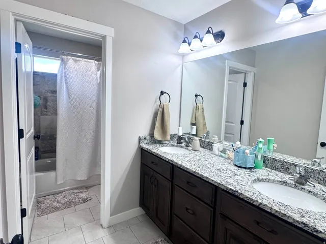 Double vanity with undermount sinks, stone countertop, and dark wood-finish cabinetry