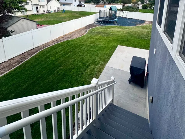 Expansive backyard with a manicured lawn, full privacy fencing, and a concrete patio