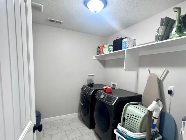 Laundry area featuring light gray tile flooring, white shelving, and a flush-mount ceiling light