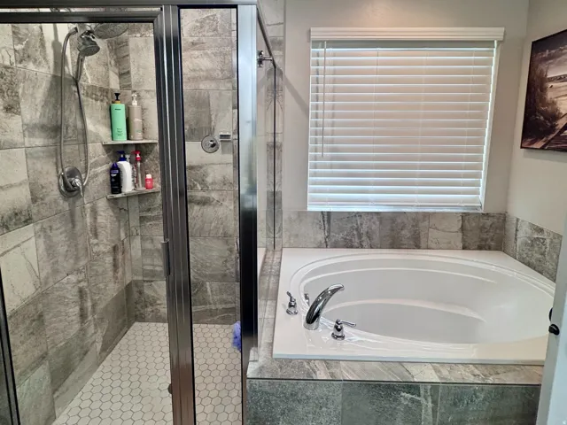 Walk-in shower with clear glass enclosure and hexagon tile flooring