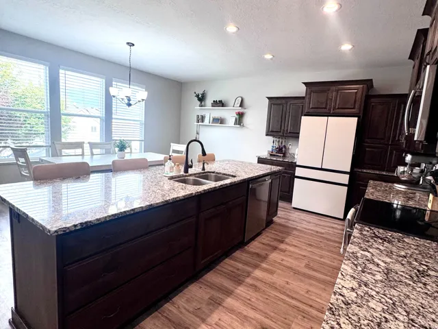 Spacious kitchen featuring an expansive center island with dual sinks, wood-finish flooring, recessed lighting, and ample cabinetry