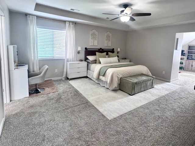Master Bedroom. Tray ceiling with recessed lighting, ceiling fan, carpet flooring, and window with blinds