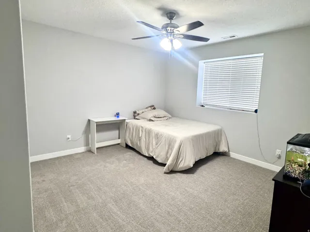 Carpeted flooring, ceiling fan with integrated lighting, and window with blinds