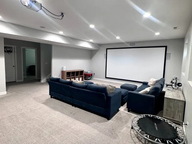 Recessed lighting illuminates a spacious room featuring a projector and a large screen