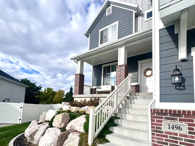 Exterior featuring blue siding, white trim accents, and a covered porch with brick-wrapped columns