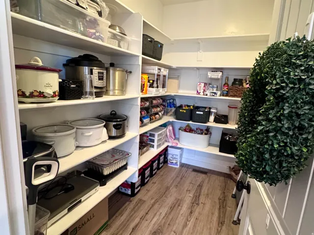 Spacious pantry featuring extensive shelving, wood-finish flooring, and recessed lighting