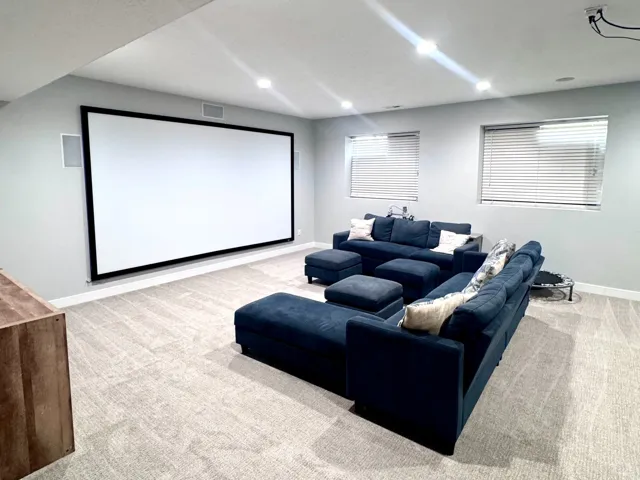 Integrated projection screen, recessed ceiling lighting, light-toned carpeting, wood-finish console, and baseboard trim