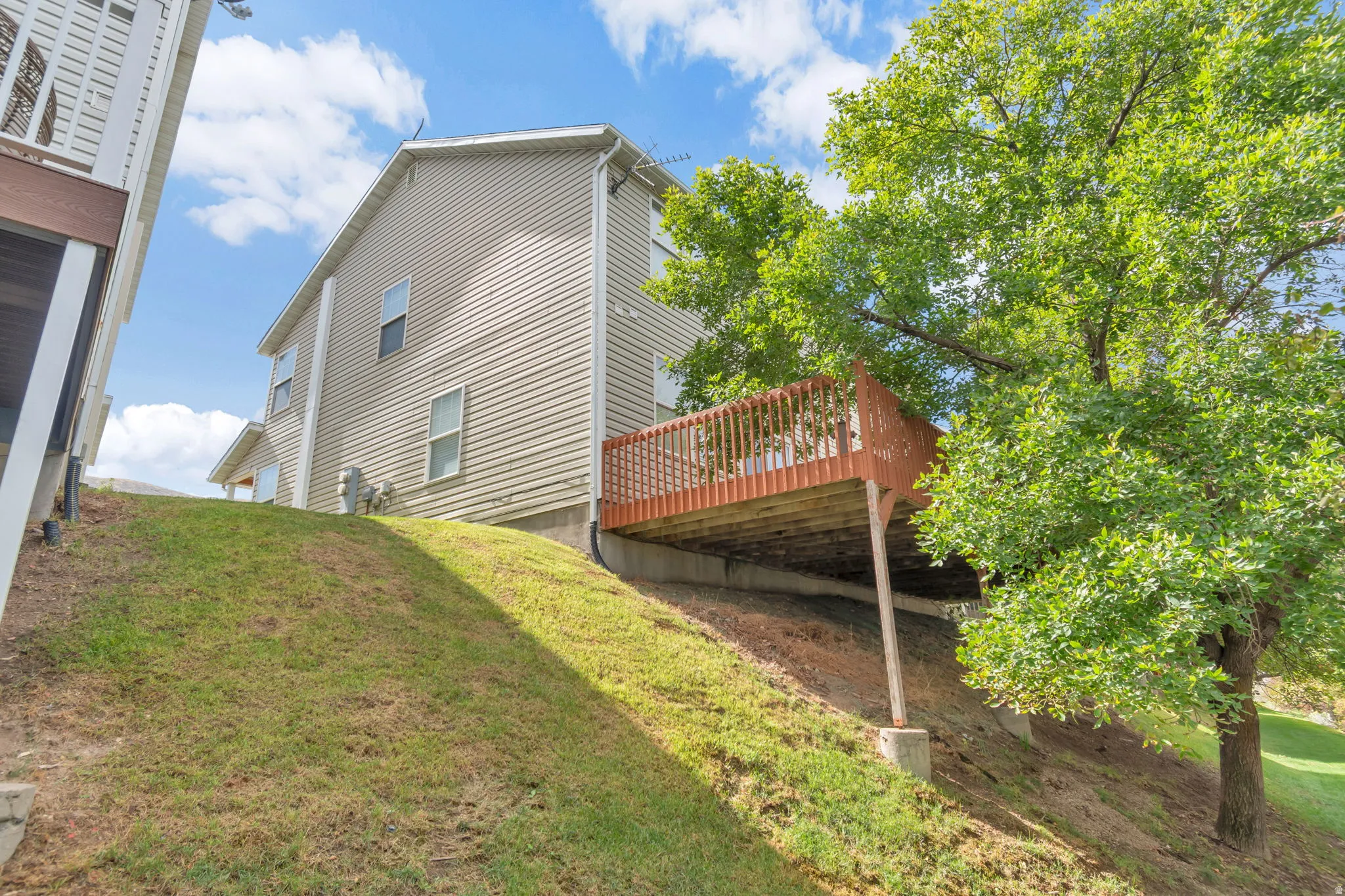 Wood-finish deck with railing, supported by concrete pillars