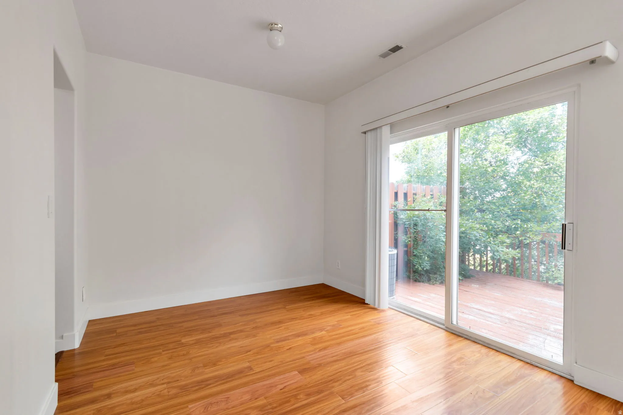 Wood-finish flooring, white painted walls, and a sliding glass door