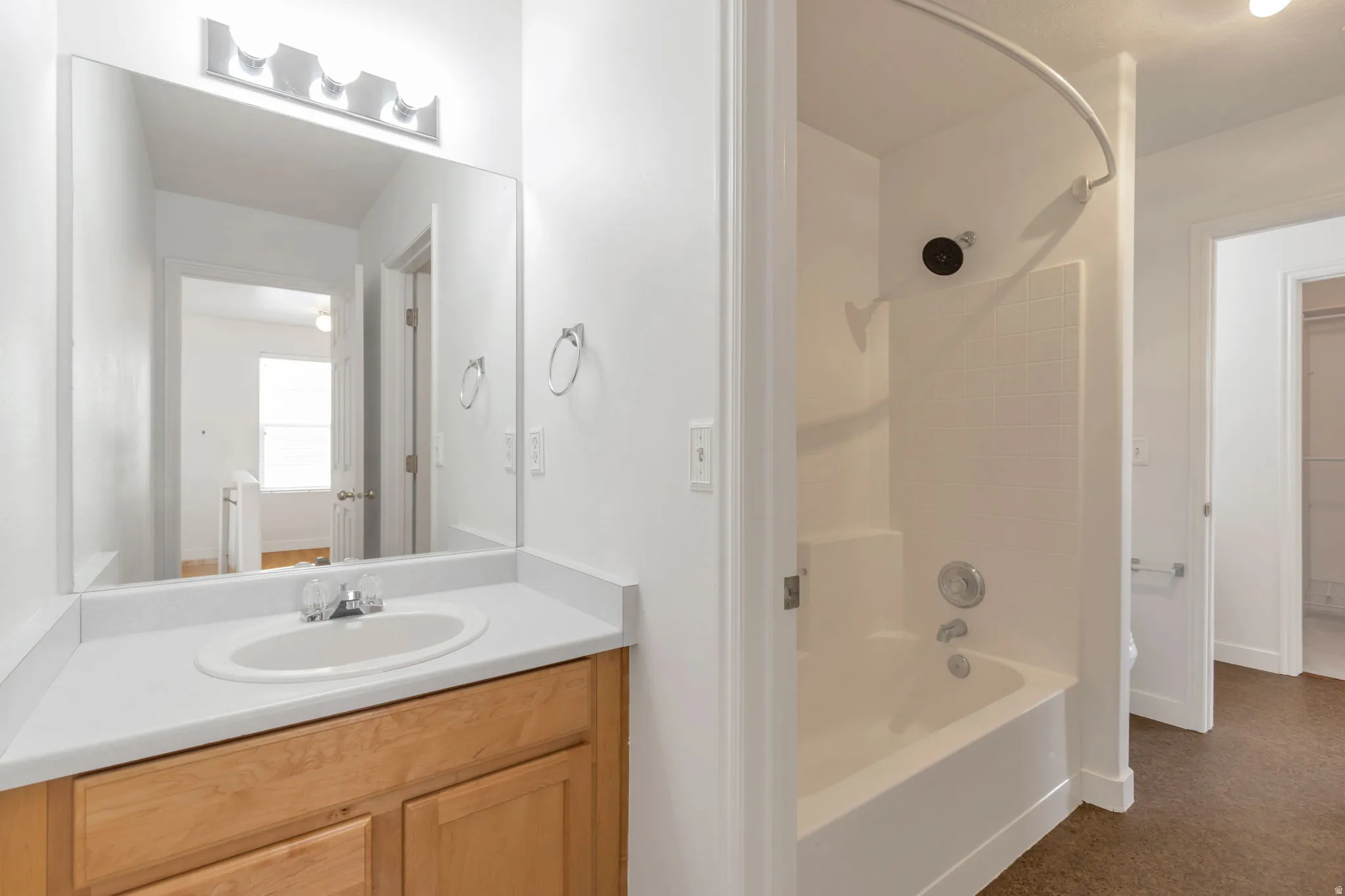 Bathroom featuring a single vanity with light wood-finish cabinetry, a white countertop, and an integrated sink