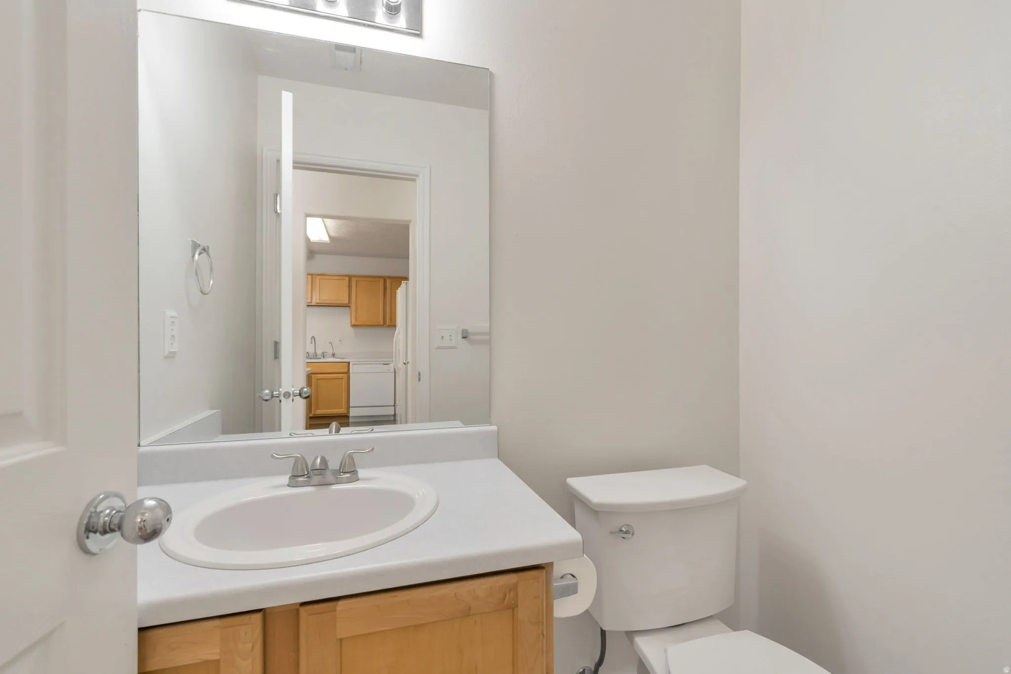 Light-colored walls with a wood-finish vanity and white countertop