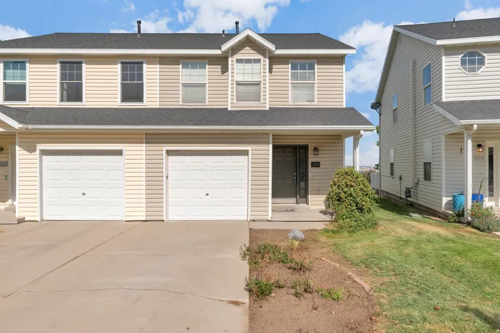 Two-story exterior with horizontal siding, a dark pitched roof, two white garage doors, and a covered entryway