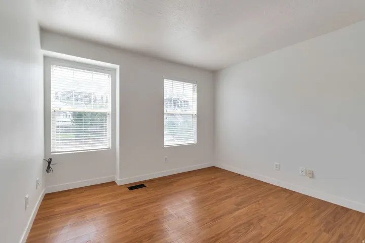 Bright room featuring wood-finish flooring and two double-hung windows with blinds