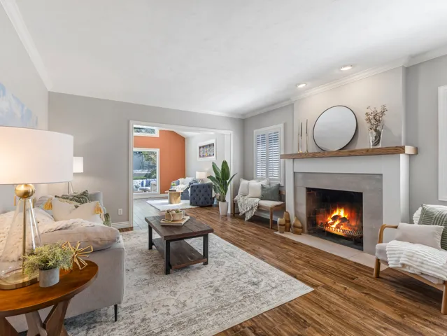 Wood-finish flooring, crown molding, a built-in fireplace with a stone surround, recessed lighting, and plantation shutters