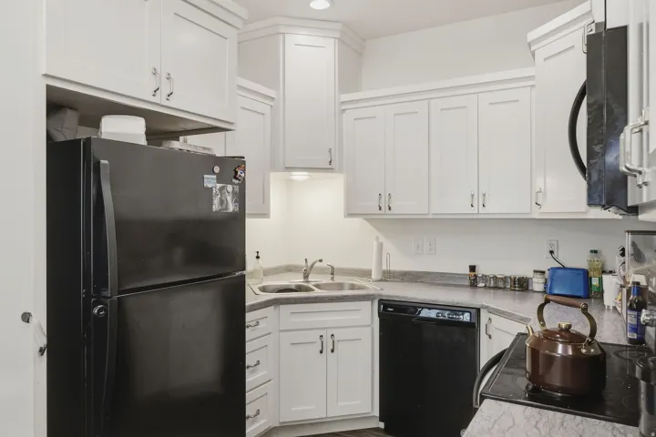 White shaker-style cabinetry, double basin sink, dishwasher, and dark finish appliances