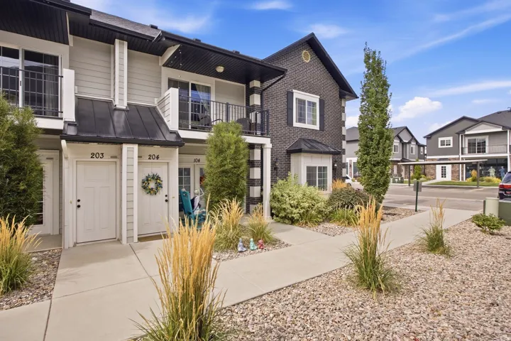 Townhome exterior featuring light siding, dark brick accents, and black metal balcony railings
