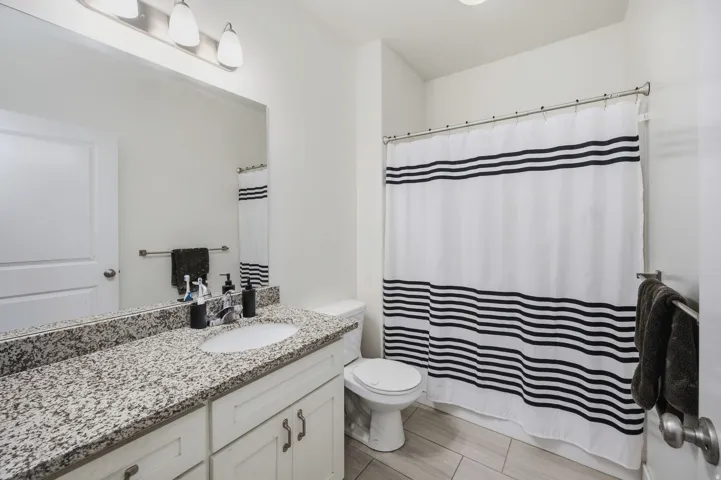 Bathroom featuring a vanity with a light granite countertop, undermount sink, and white cabinetry
