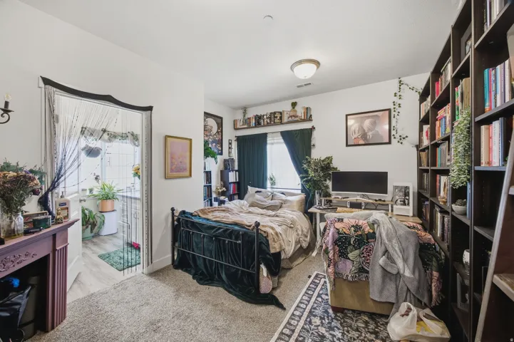 Carpeted flooring, full-height built-in shelving, sconce lighting, ceiling-mounted light fixture, and an open doorway