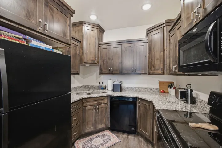 Kitchen featuring wood-finish cabinetry, speckled countertops, stainless steel double basin sink, and recessed lighting