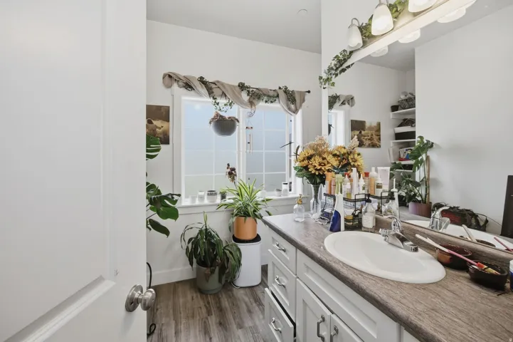 White vanity with an integrated sink, wood-finish countertop, and full-width mirror