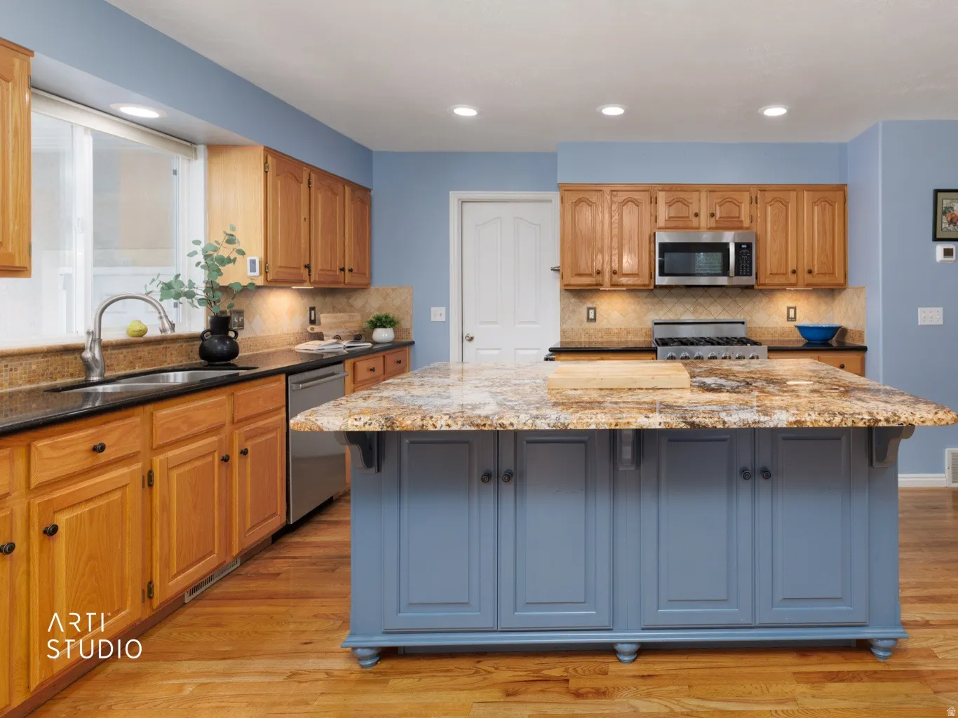 Kitchen featuring an island with stone-finish countertop, wood-finish flooring, recessed lighting, and stainless steel appliances