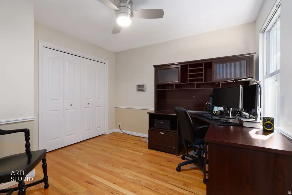 Wood-finish flooring, bi-fold closet doors, ceiling fan with integrated lighting, and a large window providing ample natural light