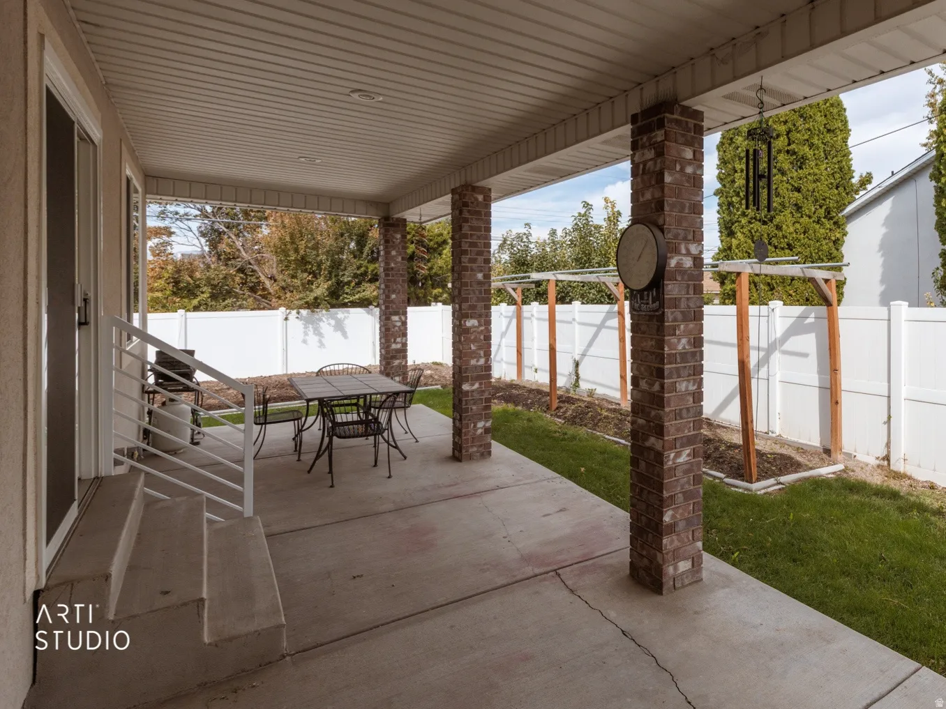 Covered concrete patio featuring brick-clad columns and recessed lighting