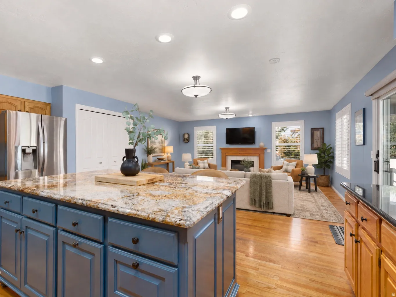 Kitchen island with stone countertop and blue cabinetry. Digitally staged furniture.