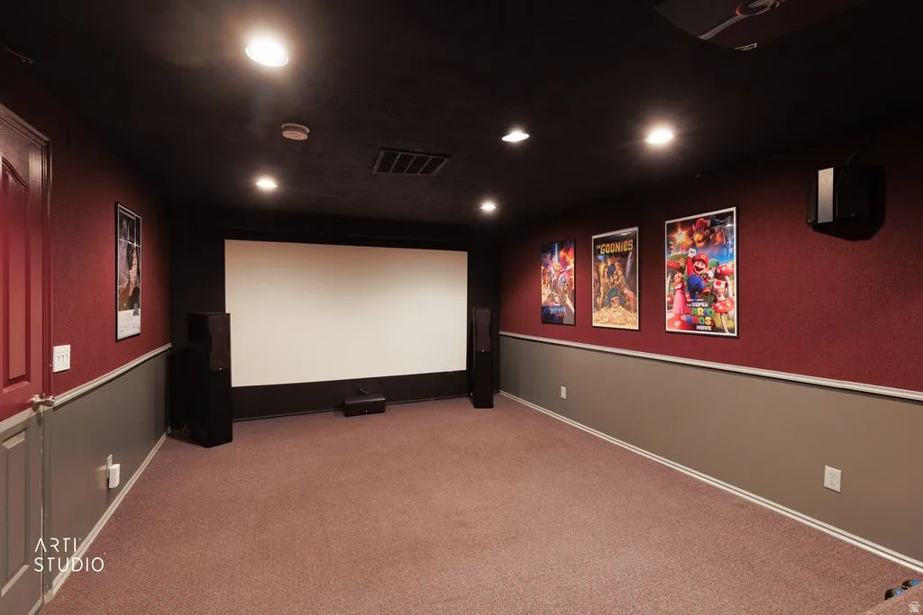 Dedicated media room featuring a large projection screen, recessed lighting, and wall-mounted speakers