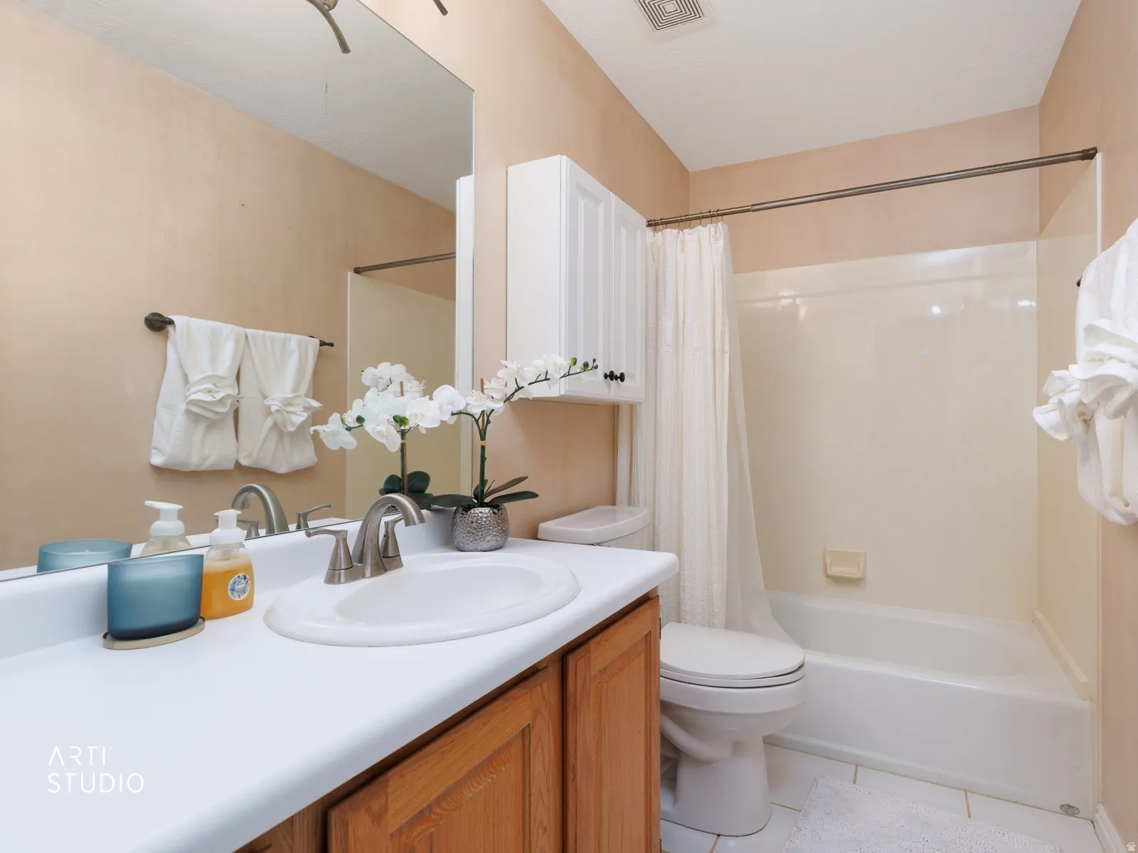 Bathroom featuring a built-in vanity with a white countertop and integrated sink, wood-finish cabinetry, a built-in mirror, and a shower-tub combination