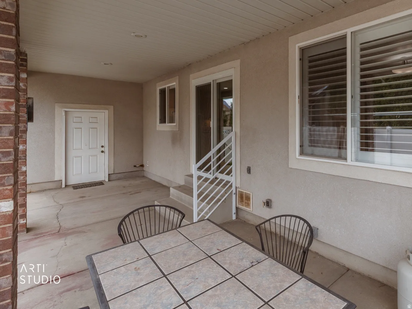Covered patio with a stucco exterior, brick column, and a sliding glass door