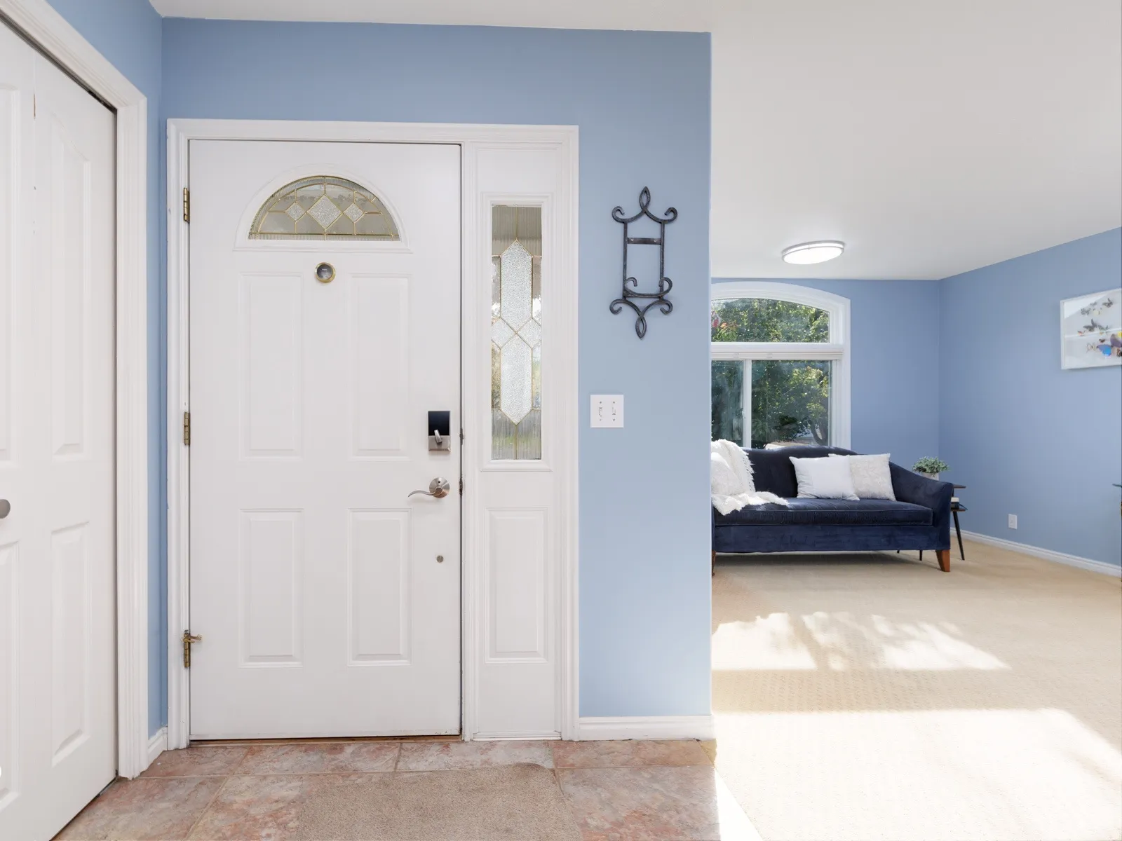 Entryway featuring a white paneled door with decorative glass, a sidelight, and a transom window