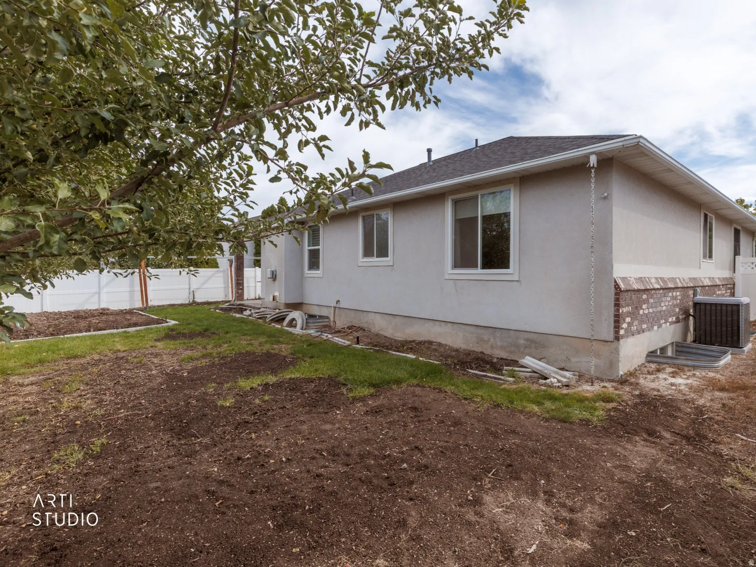 White vinyl fencing encloses the property, featuring a stucco and brick exterior, and a dark shingle roof
