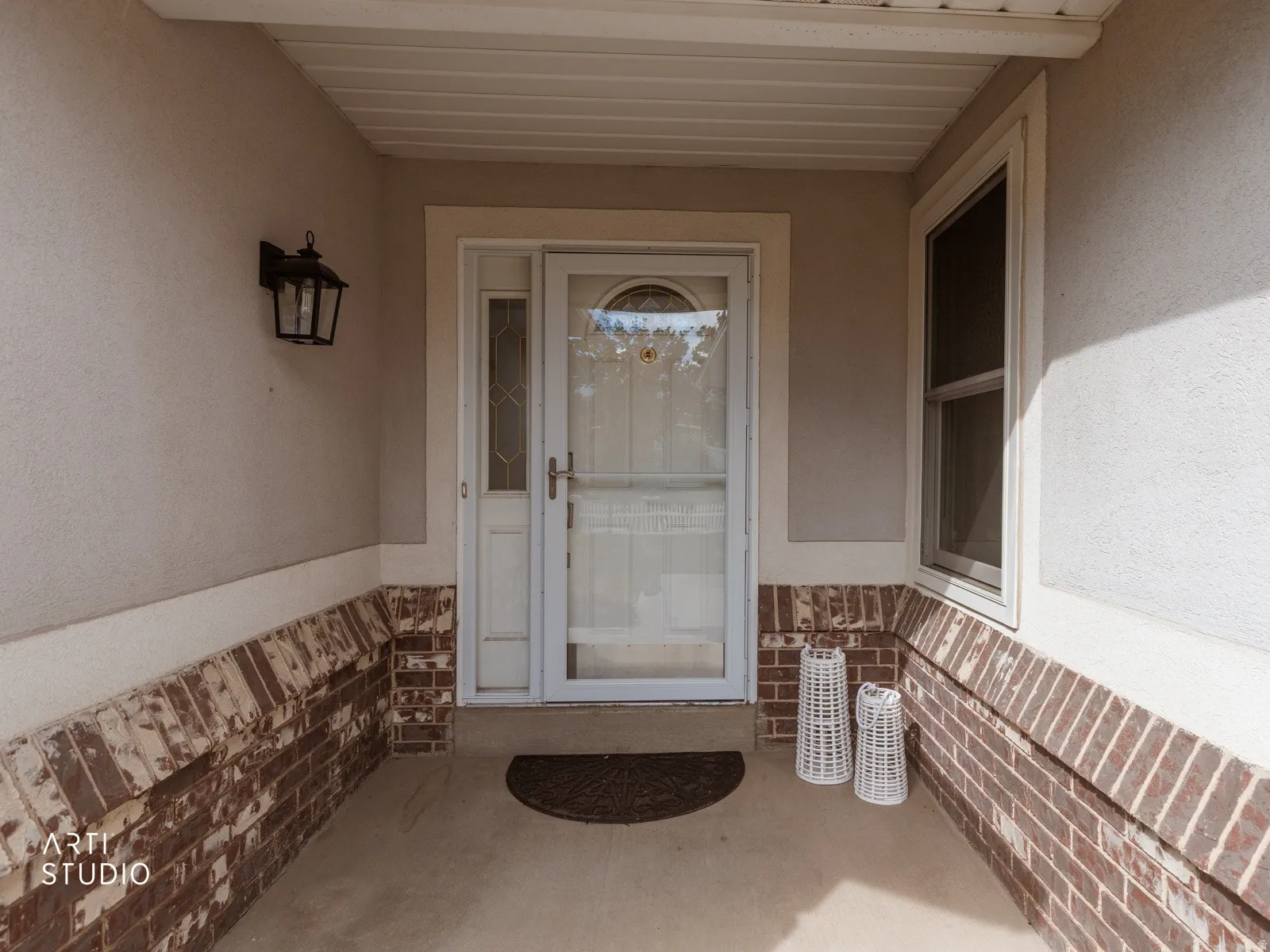 Covered entry with stucco and brick facade