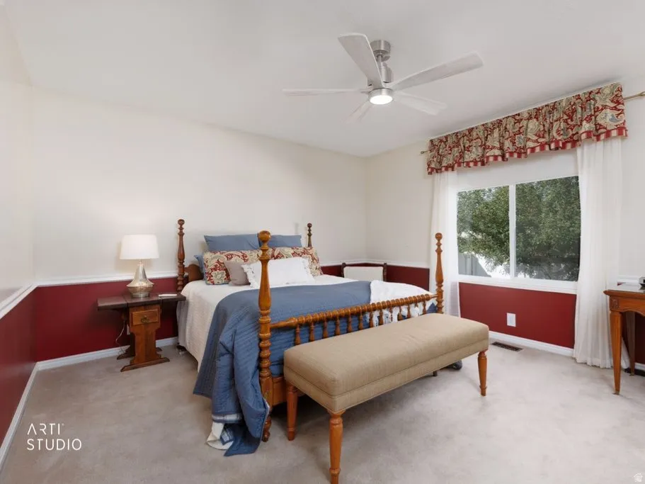Carpeted room featuring a ceiling fan with integrated lighting, a window with a valance, and two-tone wall paint